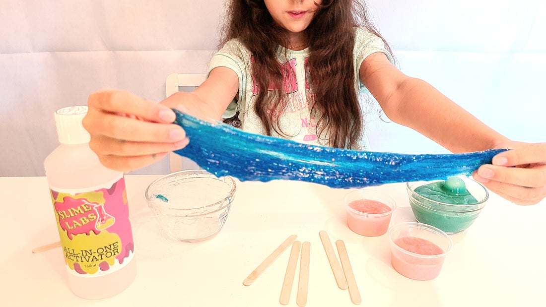 Blue Glitter Slime being stretched and Slime Labs Activator Fluid